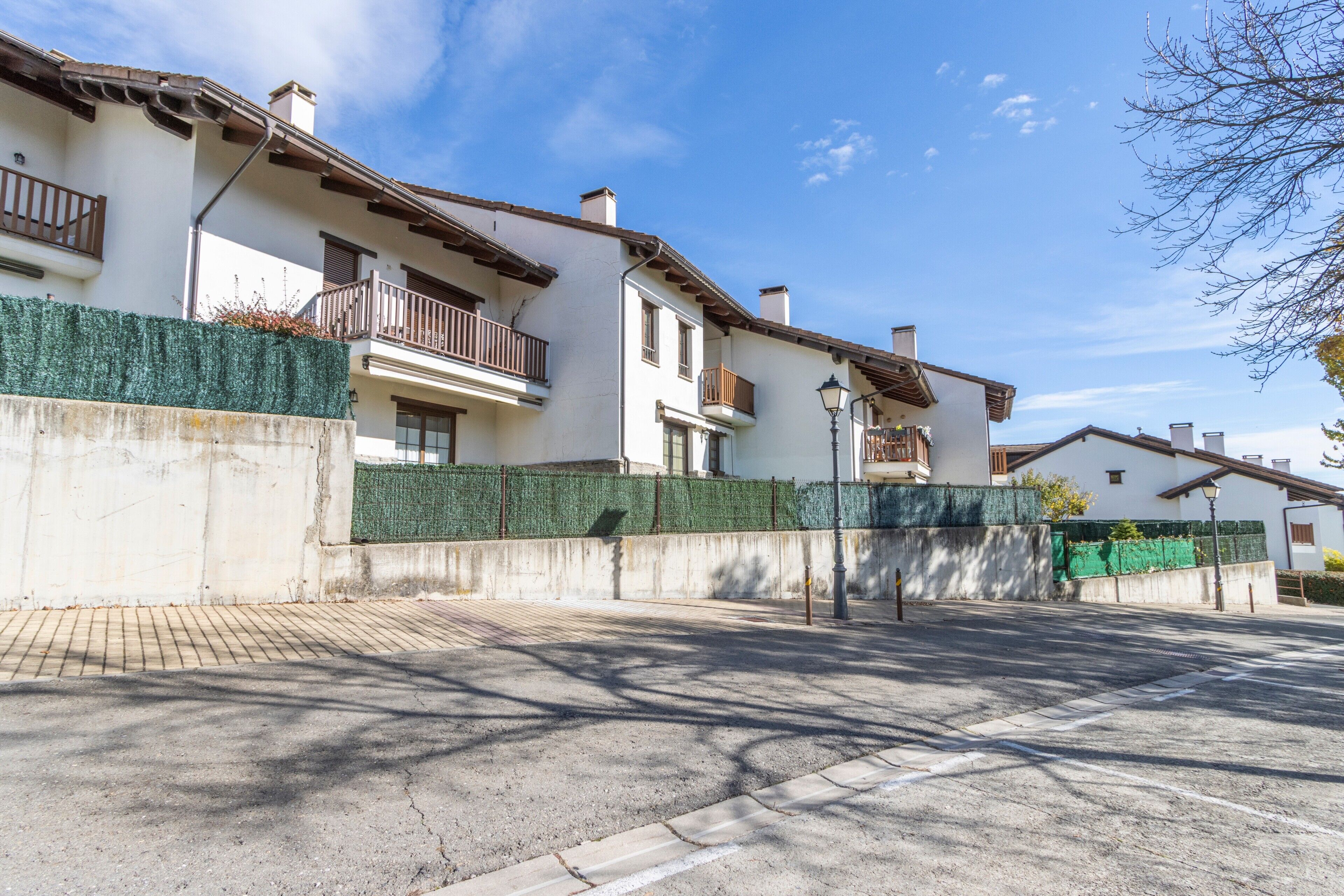 Un edificio residencial con balcones, una calle pavimentada y un cielo despejado.