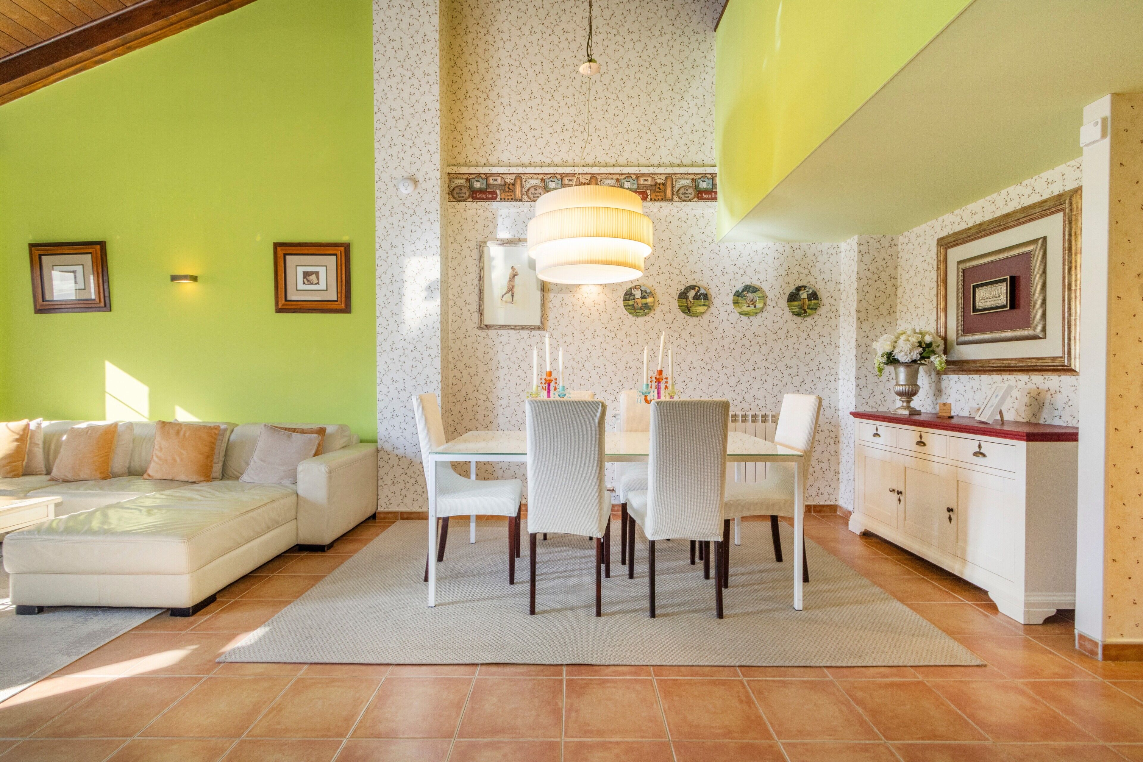 Una sala de estar con sofá, mesa de comedor, sillas y una zona de cocina con armarios y encimera.