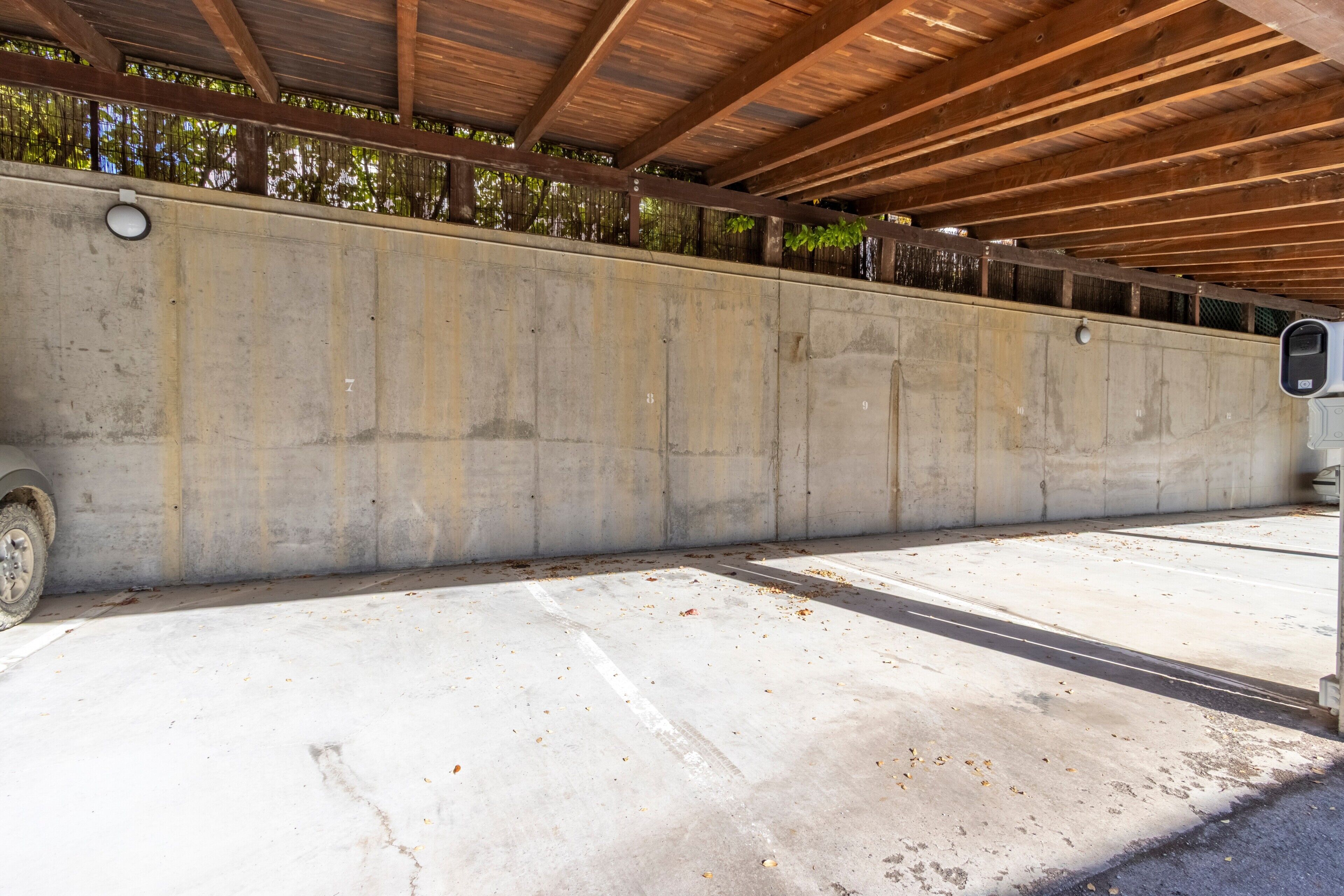 A concrete structure with a wooden ceiling, a concrete wall, and a concrete floor.