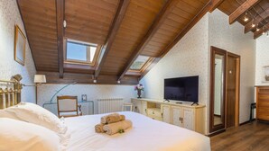Un dormitorio con una cama grande, televisión, escritorio y ventana.