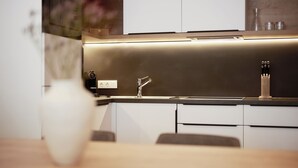 Una cocina moderna con una encimera de acero inoxidable elegante, un horno integrado y un armario blanco.