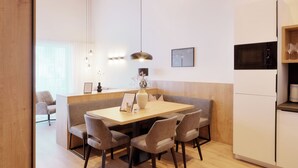 Una cocina moderna con una mesa de comedor de madera, seis sillas, una isla central, iluminación colgante, un microondas y un refrigerador.