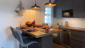 Una cocina moderna con una isla central, dos lámparas colgantes, un microondas y un lavavajillas.