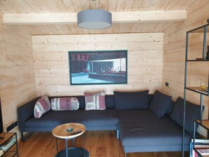 A modern interior with a dark grey sofa, a small round wooden table, and a framed picture on the wall.