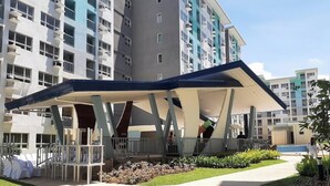 Un hôtel moderne doté d’un espace extérieur couvert avec des sièges, de nombreux balcons et d’une piscine.
