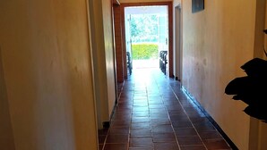 A hallway with tiled flooring, wooden ceiling beams, and doors leading to outdoor seating. - The Hill Cliff Nuwara Eliya (Nuwara eliya)