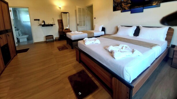 A hotel room with a large bed, two smaller beds, a wooden ceiling, and a bathroom visible through an open door. - The Hill Cliff Nuwara Eliya (Nuwara eliya)