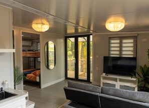 A modern living room with a sofa, TV, and a dining area with a table and chairs.