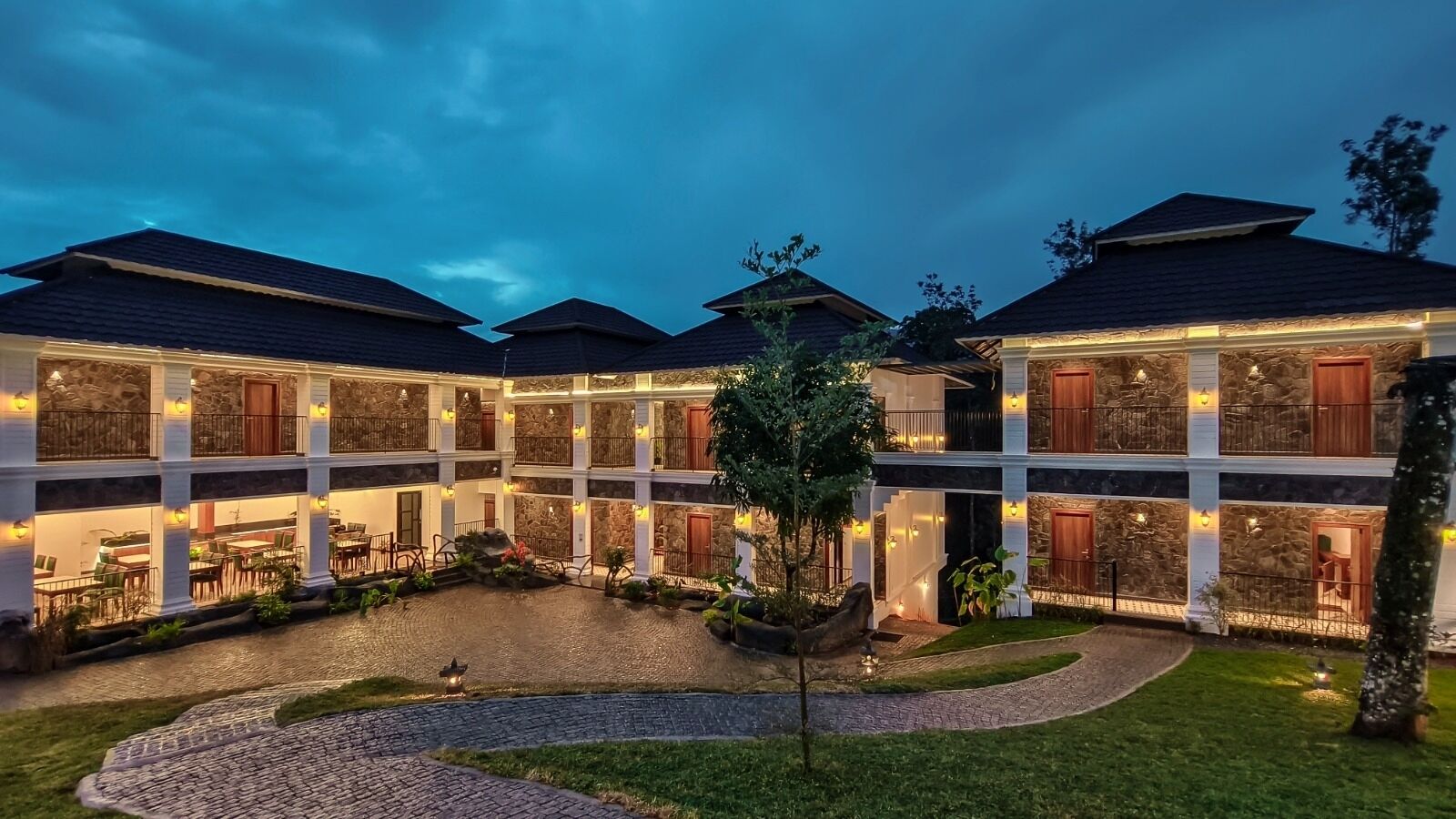 Un hotel de varios pisos con patio interior, asientos exteriores y fachada de piedra.