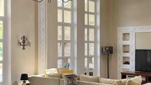 Un salon comprenant un canapé, une lampe, un téléviseur et un élément décoratif mural.