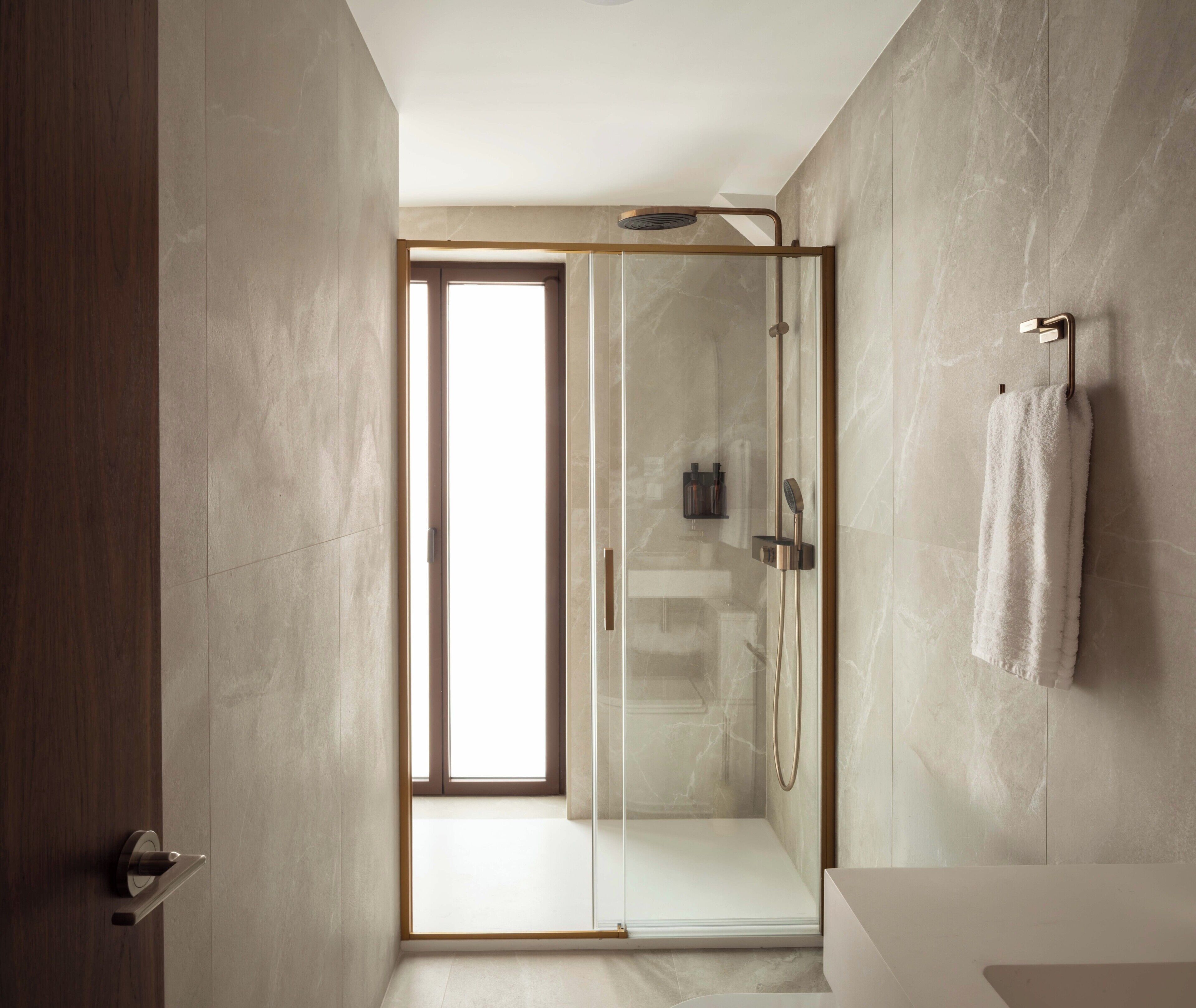 Une salle de bain moderne avec une douche à parois de verre, un porte-serviettes et un meuble-lavabo apparent.