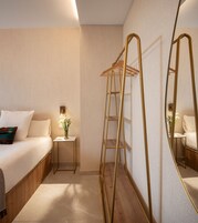 Une chambre d’hôtel avec un lit, une table de chevet, un miroir et une échelle en bois.