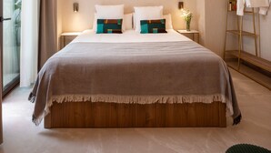 Une chambre d’hôtel avec un grand lit, une table de chevet avec une lampe, une petite table d’appoint avec un vase et un porte-vêtements.