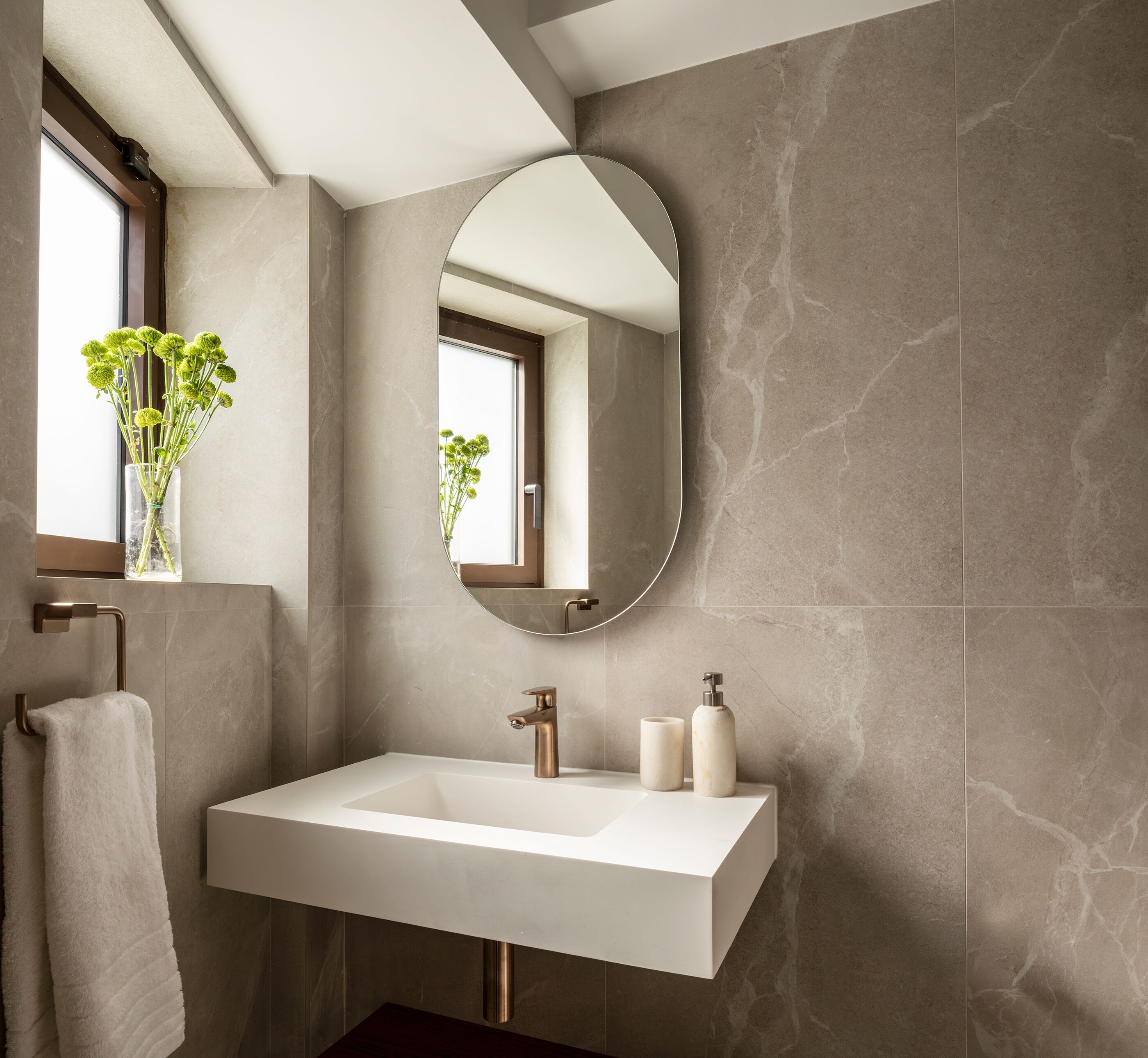 Un baño moderno con un espejo grande, un lavamanos blanco y un perchero para toallas.