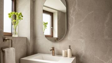 Un baño moderno con un espejo grande, un lavamanos blanco y un perchero para toallas.