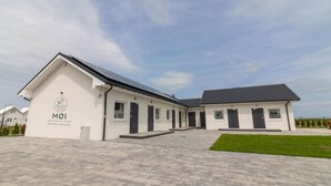 A modern building with a flat roof, a sign reading "MØI Apartments by Jamo," and a paved courtyard. - Comfortable Holiday Homes in Mielno (Mielno)