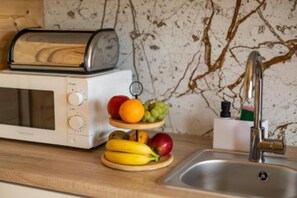 Una cocina con un tostador, una exposición de frutas y un lavamanos.