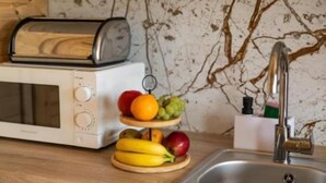 Een keuken met een broodrooster, een spoelbak en een presentatie van fruit.