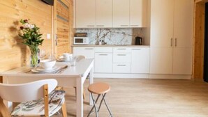Une cuisine de taille réduite avec des meubles blancs, un four à micro-ondes et un pare-feu en marbre.