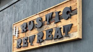 A wooden sign with the words "Rustic Retreat" in large, bold letters.