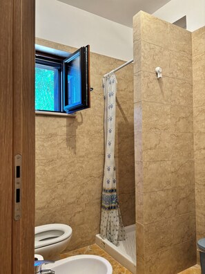 Een badkamer met douche, toilet en wastafel.