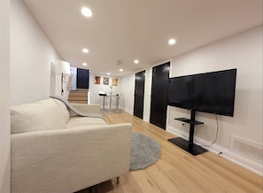 A modern living room with a sofa, a TV, and a staircase leading to another level.