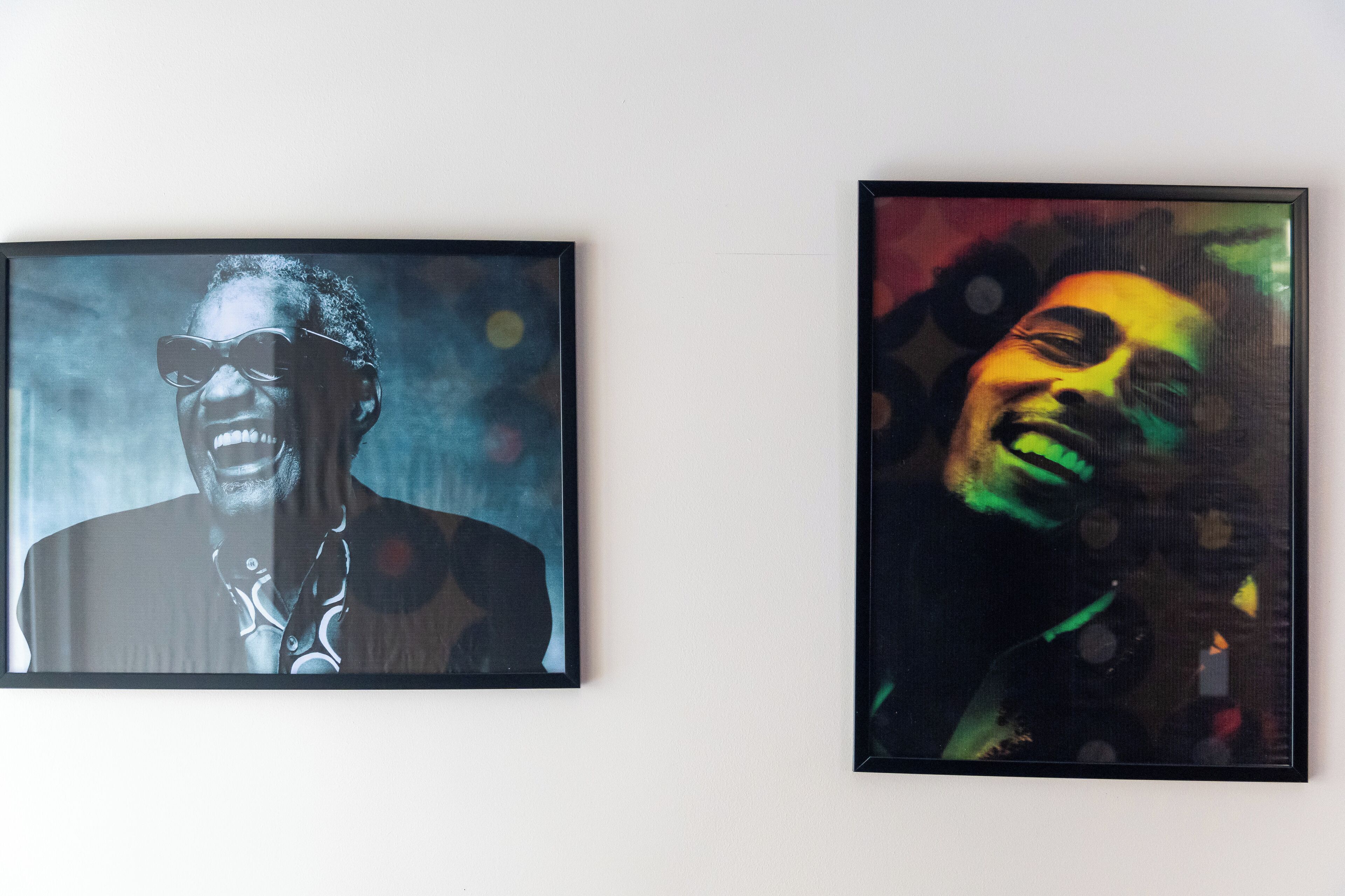 Two framed portraits of a person with a blurred face, one in black and white and the other in color, displayed on a wall.