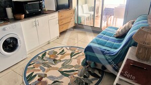 A compact room with a bed, a washing machine, a microwave, a television, and a small table with a lamp. - Studio 4 personnes, terrasse vue mer et parking (Sète)