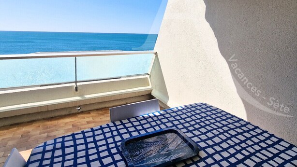A balcony with a view of the sea, a tiled table, and a chair. - Studio 4 personnes, terrasse vue mer et parking (Sète)