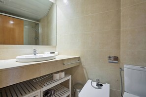 Une salle de bain avec un lavabo, un miroir et des toilettes.