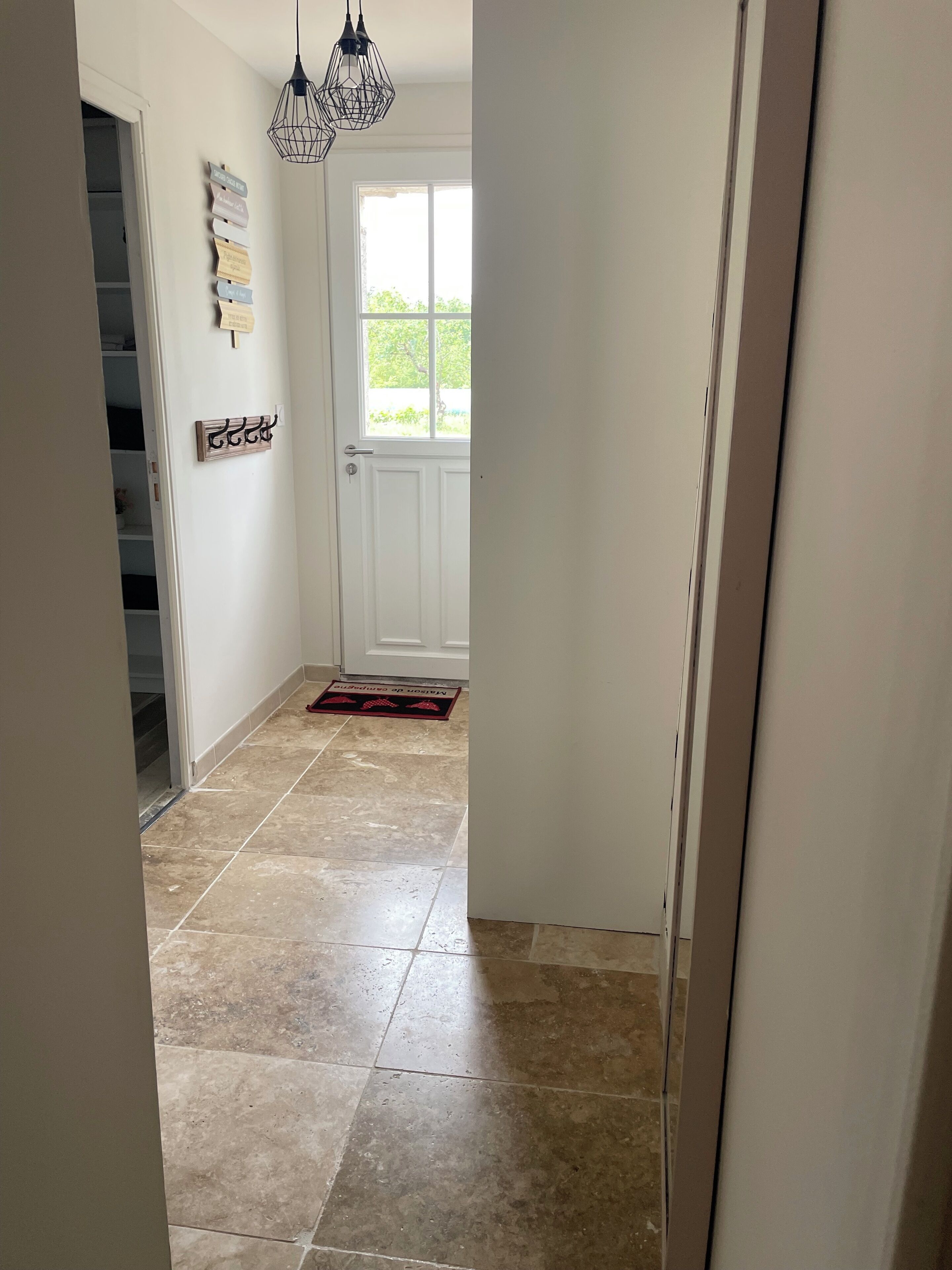 A hallway with a white door, a window, and a tiled floor.