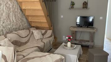 Un salon chaleureux avec un escalier en bois, un canapé, une table basse et un téléviseur.