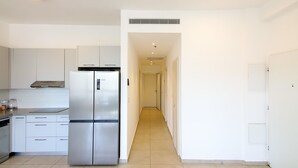 A modern kitchen with a stainless steel refrigerator, white cabinets, and a tiled floor. - Rivka I - Two Bedroom Apartment, Sleeps 4 (Jerusalem)