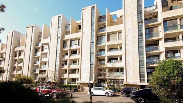A multi-story residential building with balconies, a parking area, and a clear sky. - Rivka I - Two Bedroom Apartment, Sleeps 4 (Jerusalem)