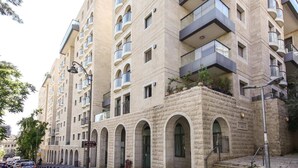 Un edificio de varios pisos con balcones, ventanas de arco y fachada de piedra.