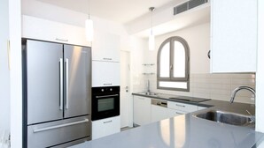 Una cocina moderna con electrodomésticos de acero inoxidable, armarios blancos y una isla grande con un lavamanos.