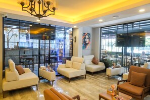 Un salon moderne avec des canapés, un lustre et de grandes fenêtres.