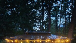 Un área de estar al aire libre con pérgola, luces colgantes y una mesa redonda.