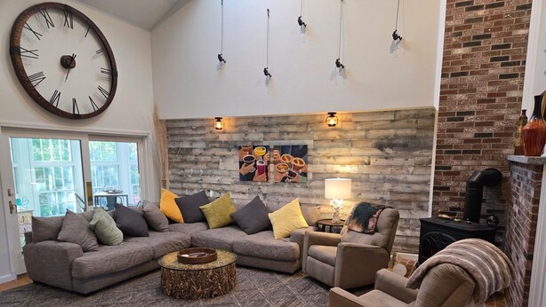 Una sala de estar con un sofá modular, una mesa de centro redonda, una chimenea y un reloj de pared grande.
