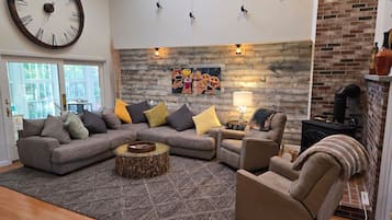 A living room with a sectional sofa, a round coffee table, a fireplace, and a large wall clock.