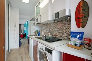 Een keuken met een wasmachine, een magnetron en een koffiezetapparaat.