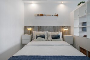 Een moderne slaapkamer met een bed, nachtkastjes en een decoratief item aan de muur.