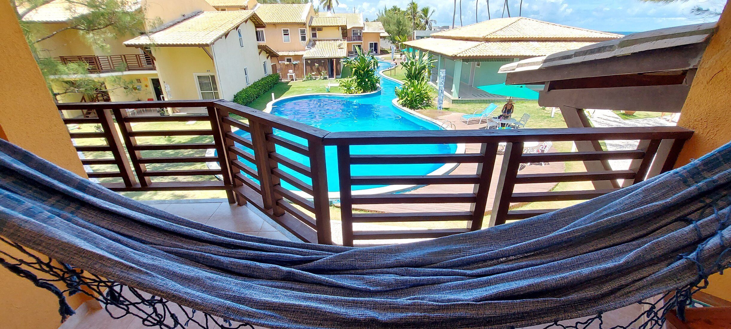 Una hamaca en un balcón con vistas a una piscina y edificios cercanos.