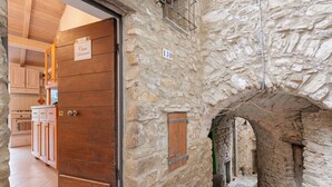 A stone building with a wooden door, a kitchen with cabinets, and a stone wall with a number sign.