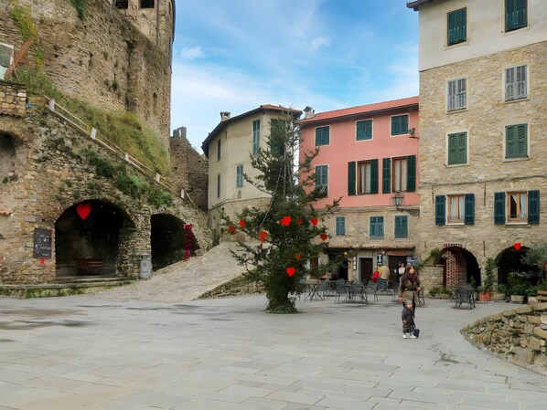 A stone building with a staircase, a tree with red decorations, and a clear sky.