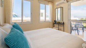 Une chambre avec un grand lit, deux fenêtres, un balcon et un miroir.