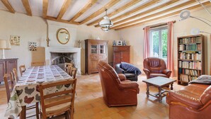 A living room with a fireplace, leather furniture, a dining table, and a bookshelf.