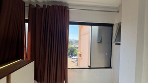 A room with a window, curtains, and a view of buildings outside. - Golden Thermas Residence (Caldas Novas)