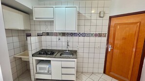 A compact kitchen with white cabinets, a built-in microwave, and a sink. - Golden Thermas Residence (Caldas Novas)