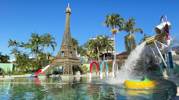 A water park with a replica of the Eiffel Tower, a water slide, and a pool with a yellow inflatable tube. - Golden Thermas Residence (Caldas Novas)